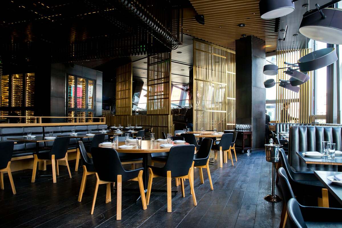 Comedor de restaurante con mesas, sillas de madera y luz cálida sobre el suelo