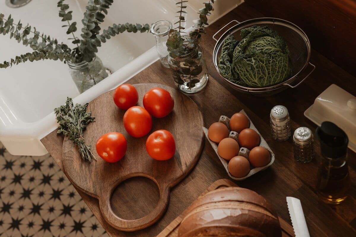 Ingredientes de una receta ordenados sobre una tabla: tomates, huevos, hierbas y col